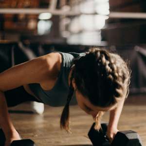 woman doing pushup with dumbbell