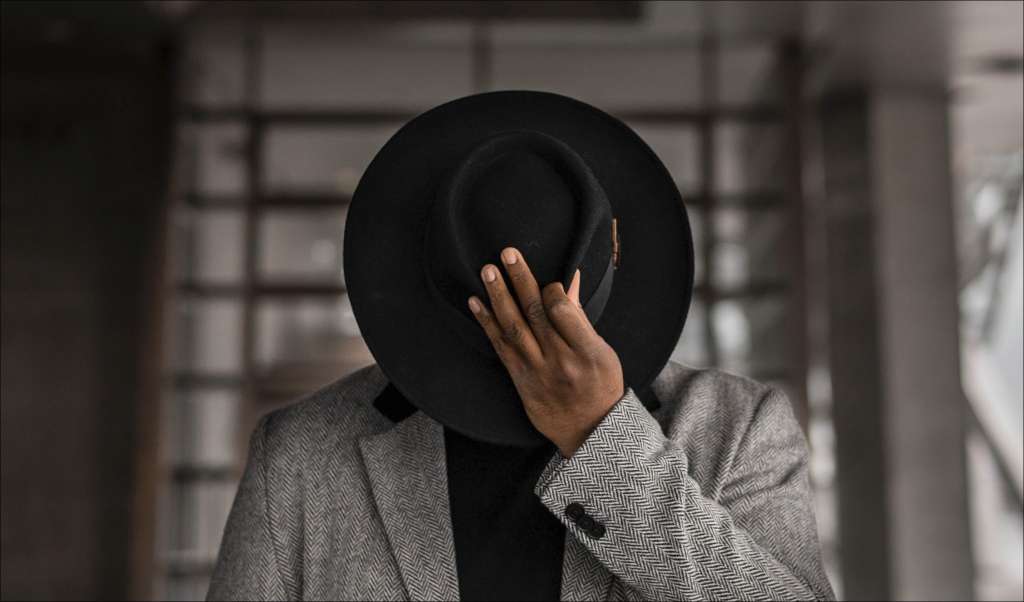 a man hiding behind a hat