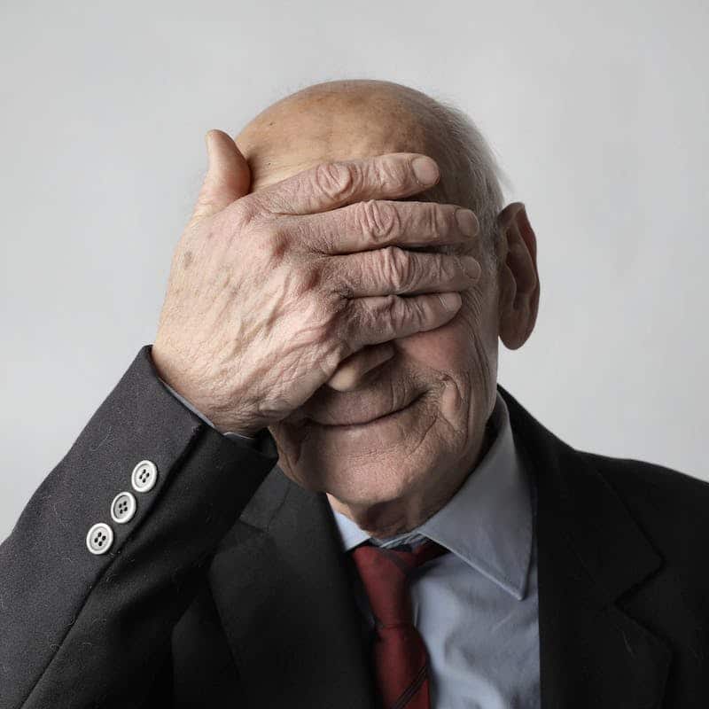 an old man covering his face with his right hand