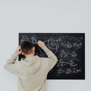 man rubbing his head while solving an equation