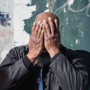 a bald man covering his face